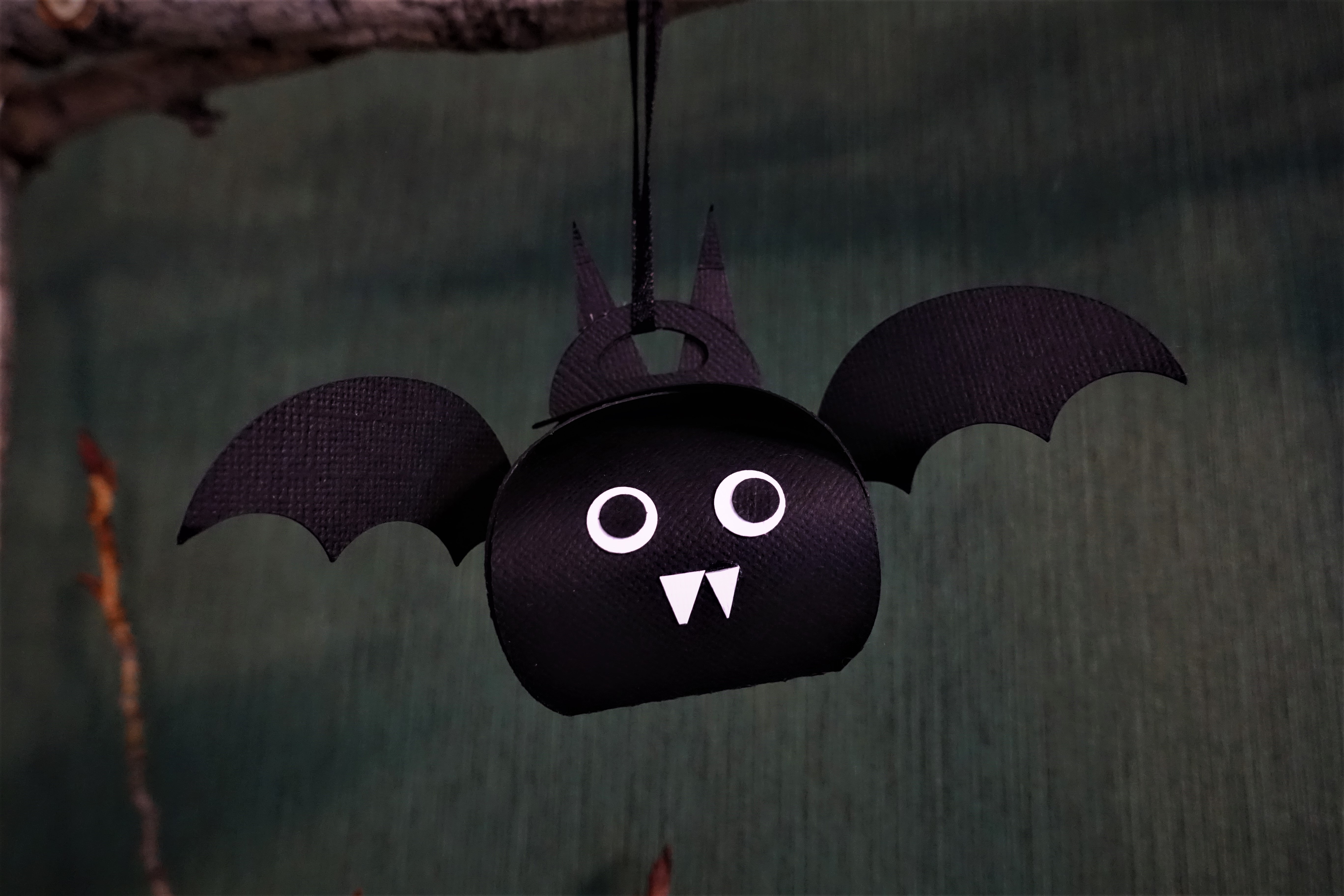 A Halloween paper bat favor box hanging on a string