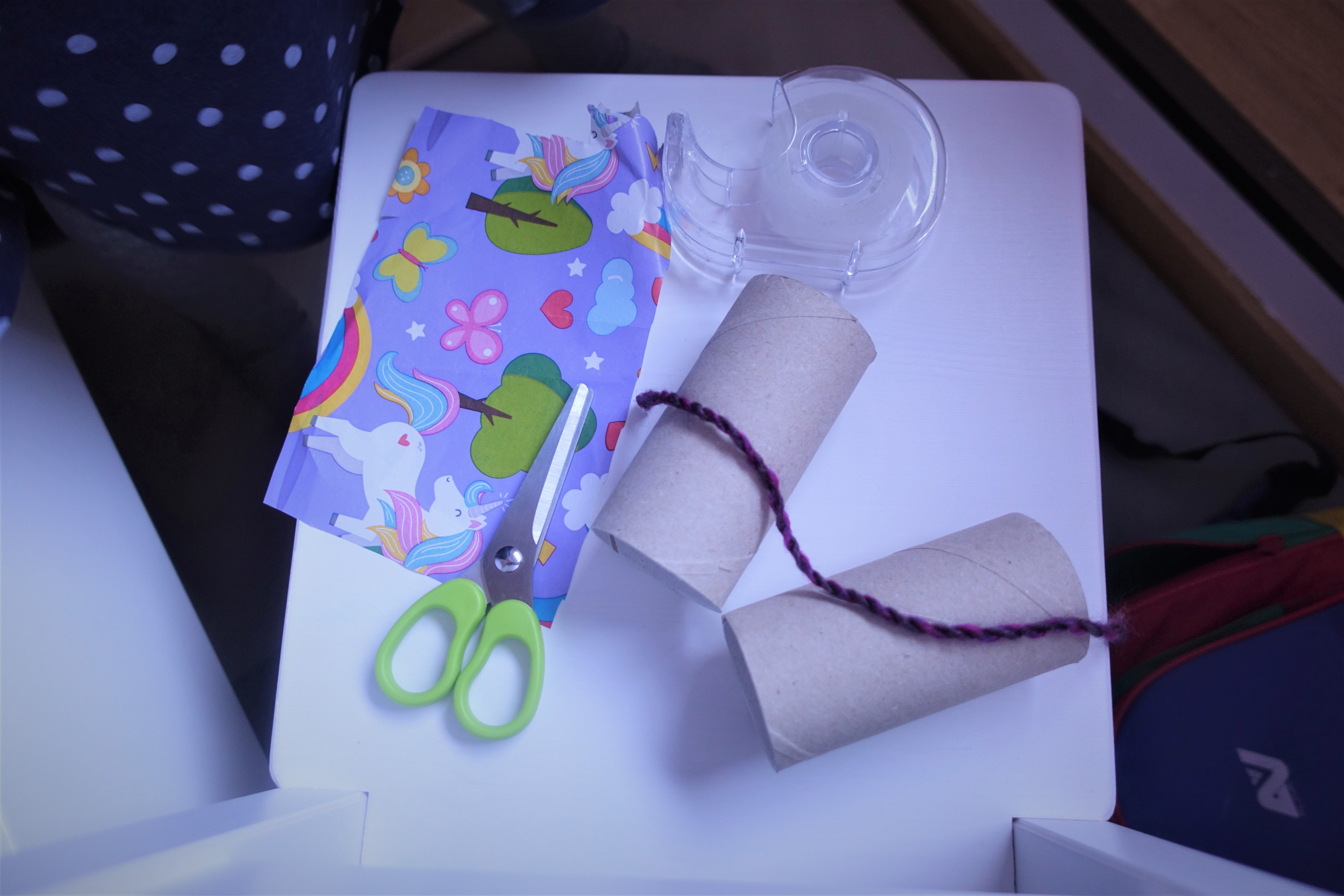 Scissors, tape, wrapping paper, a string and two empty toilet paper rolls are required to make the binoculars.