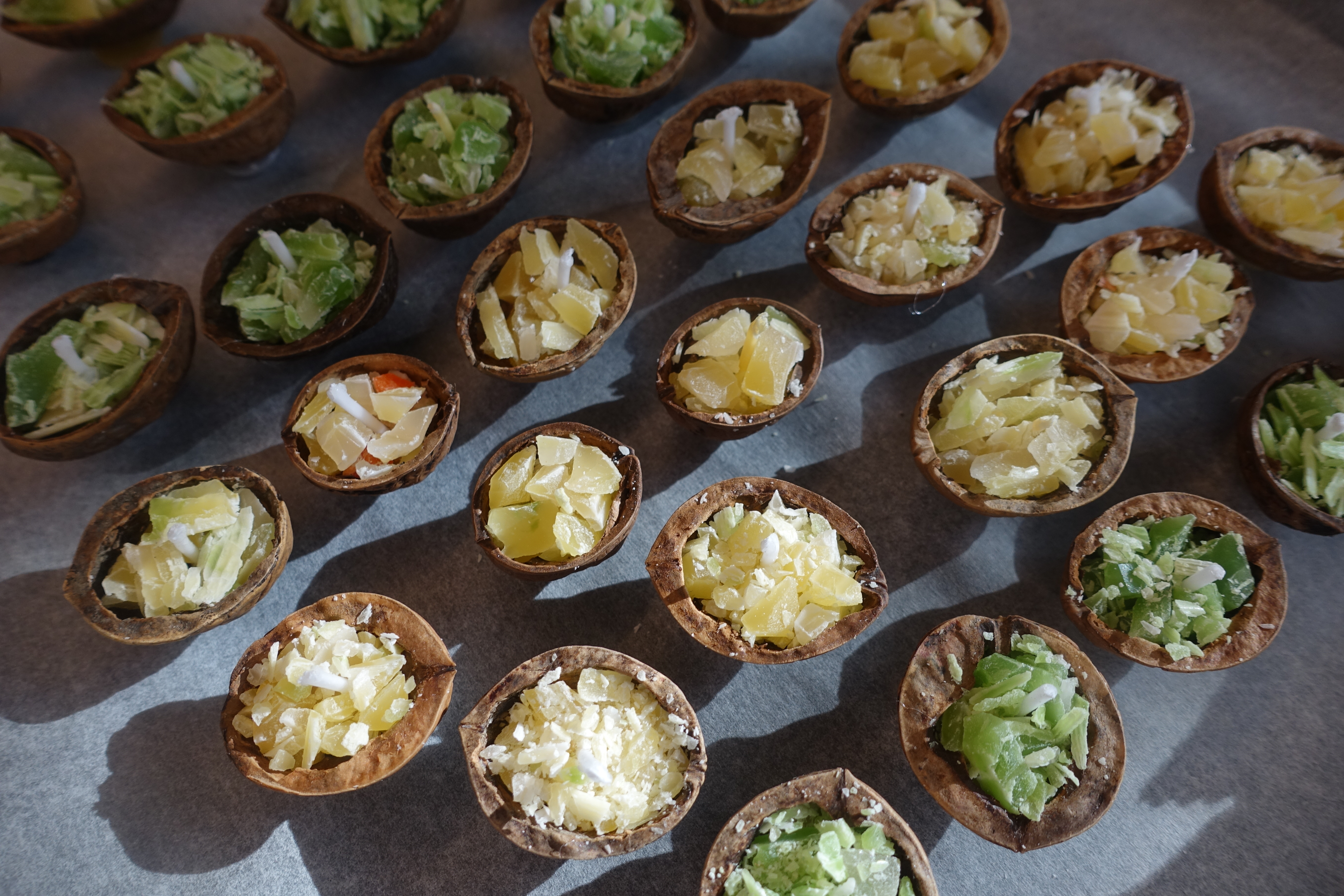 Collection of green and yellow candles made out of walnuts