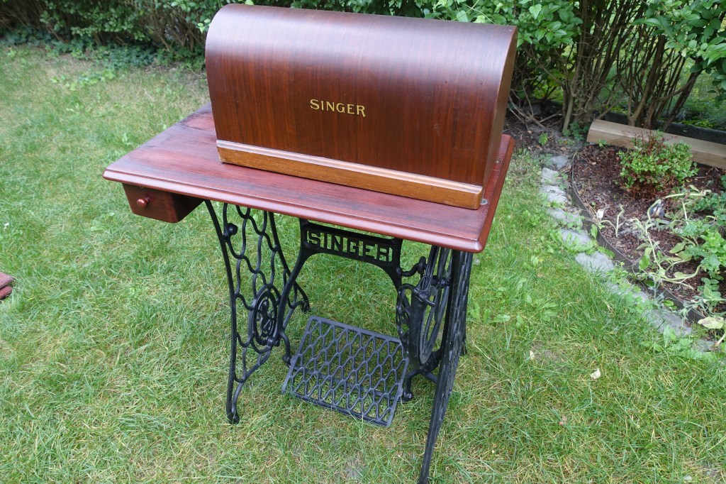 A photo of a vintage singer sewing machine standing outside